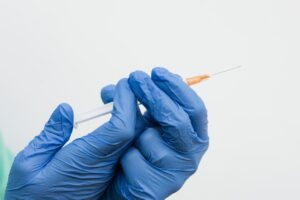 Close-up of Holding a Syringe While Wearing Blue Gloves